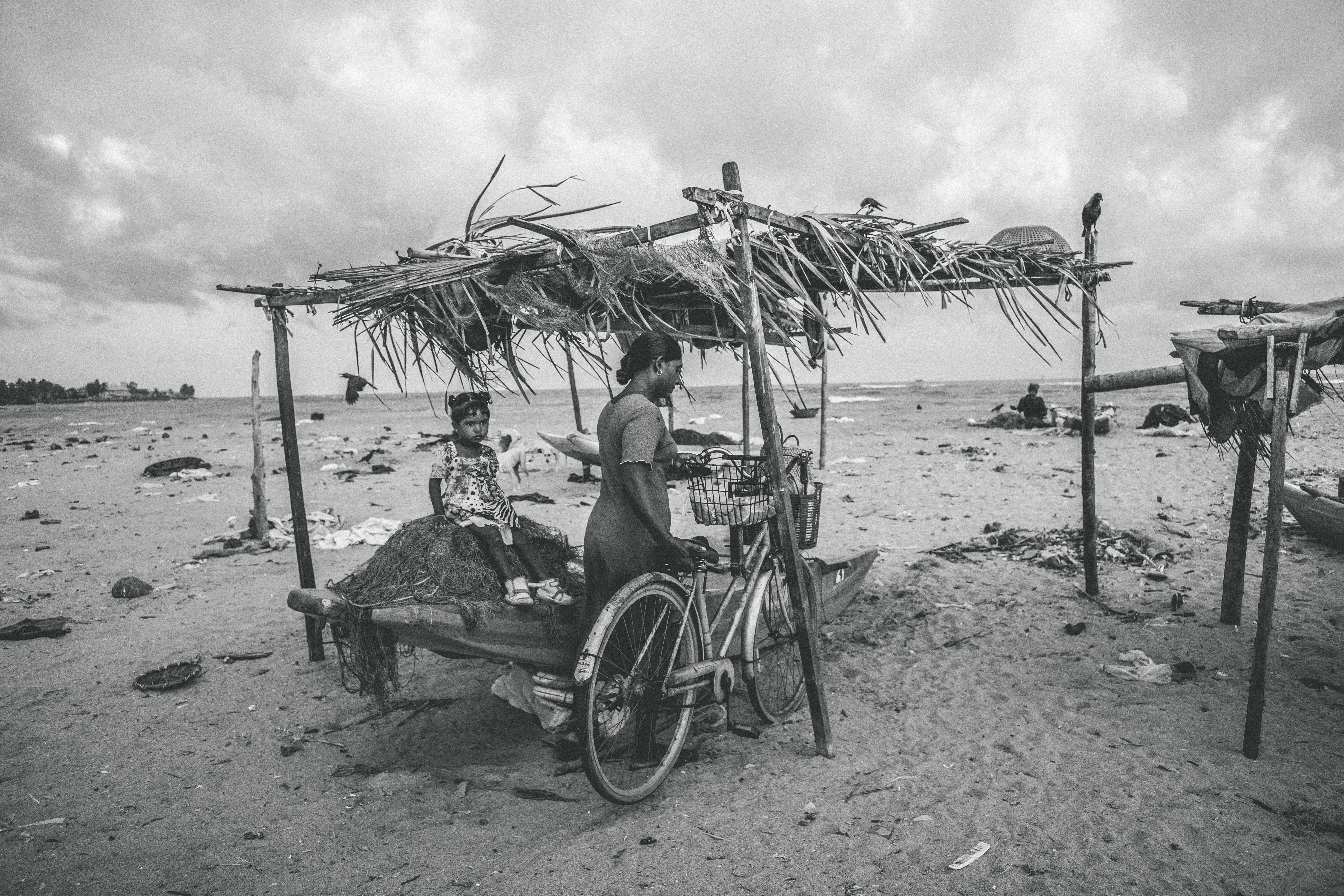 grayscale photo of woman sitting on beach chair under umbrella